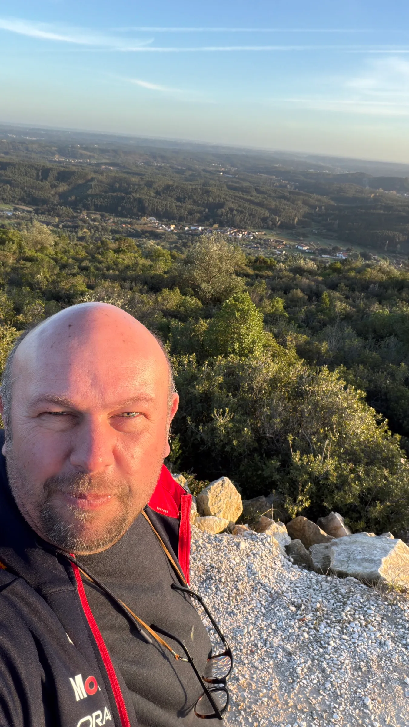Arnold on a hilltop in Portugal at golden hour, green valley behind him